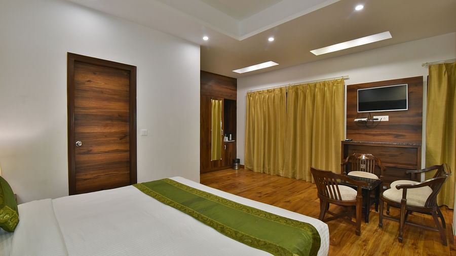 A large bed placed in front of two sofas at the Luxury Room Without Balcony at DLS Highland Resort and Spa, Mussoorie.